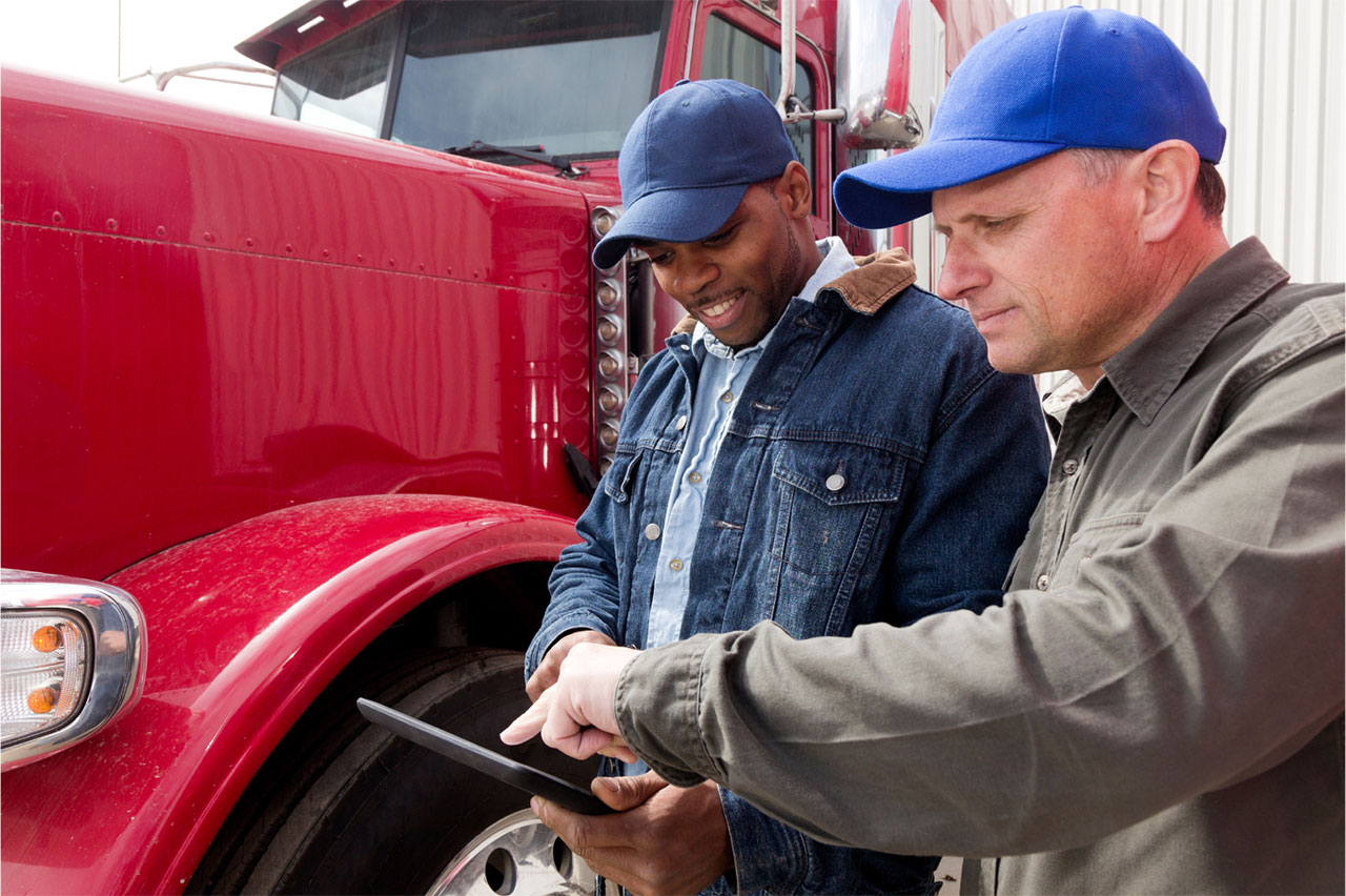 Two men reviewing DQM on a tablet in front of a truck