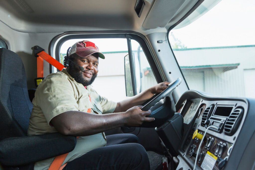 Commercial truck driver smiling behind the wheel during driver onboarding and safety screening