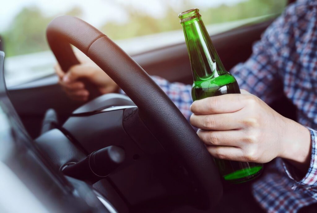 Commercial driver holding a beer while seated behind the wheel